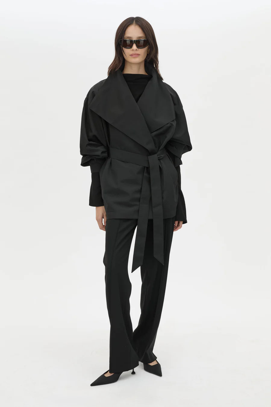 Woman wearing a black outfit with a belt on a white background