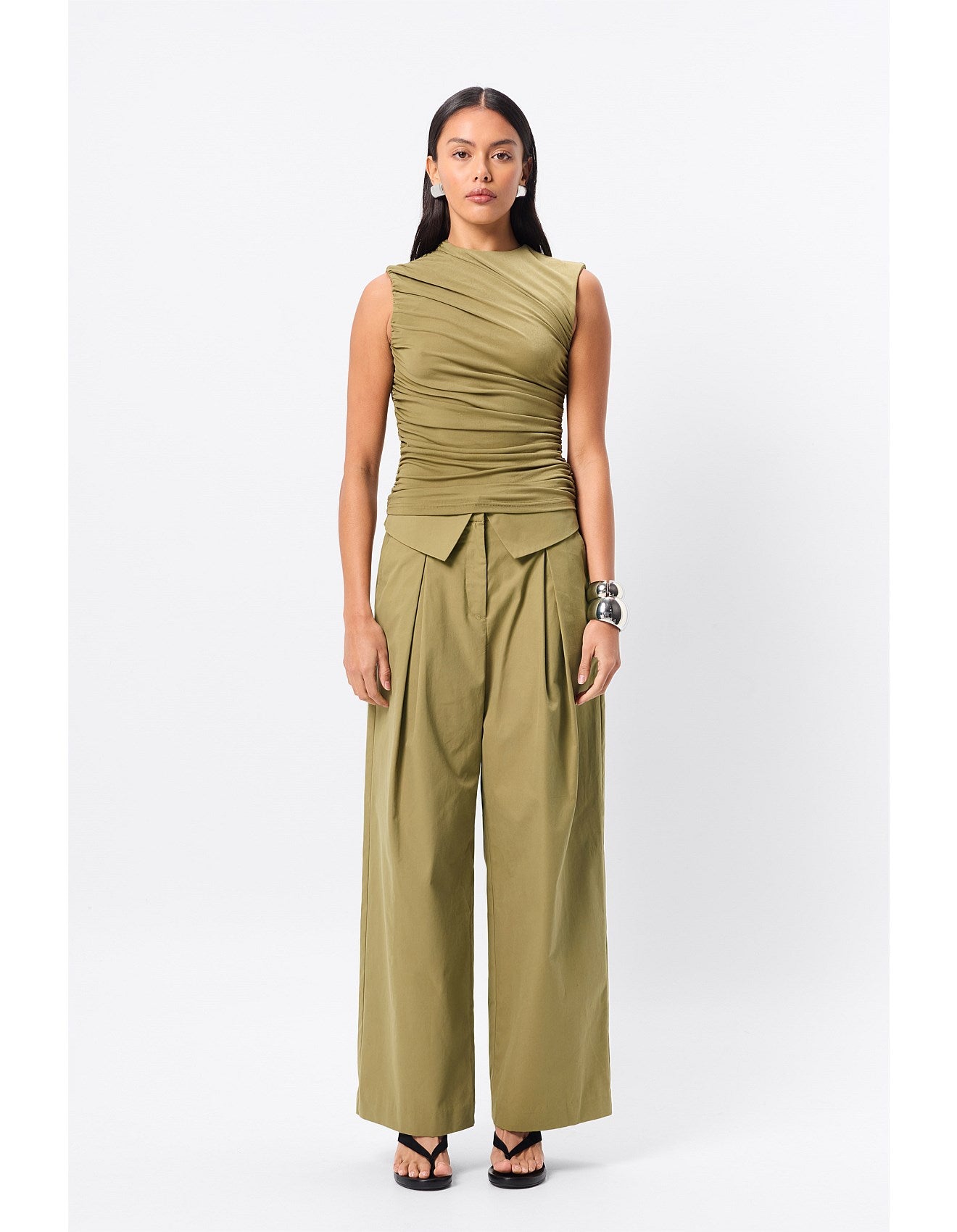Woman standing in an olive top.
A sleek essential with a sculptural edge, the Sole Purpose Tank in Black brings modern ease to everyday dressing. Cut from a soft stretch jersey fabrication, this sleeveless style features gathered detailing through the sides and bodice, creating a flattering, body-skimming silhouette. Designed with a high round neckline and half lining through the body, it delivers both comfort and structure. Pair back with tailoring or relaxed separates for effortless sophistication.