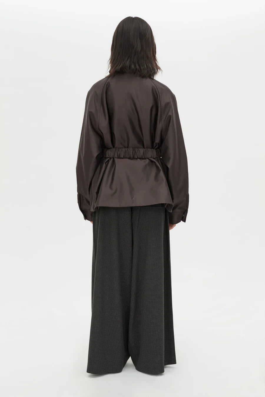 Person wearing a brown jacket and wide-leg pants on a white background