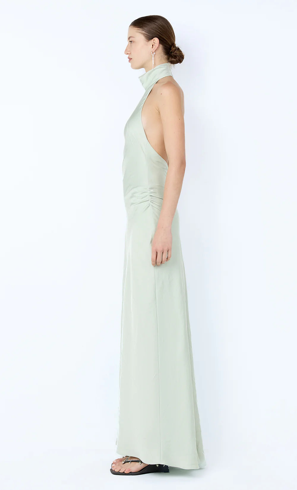 Woman wearing a light green halter neck dress on a white background