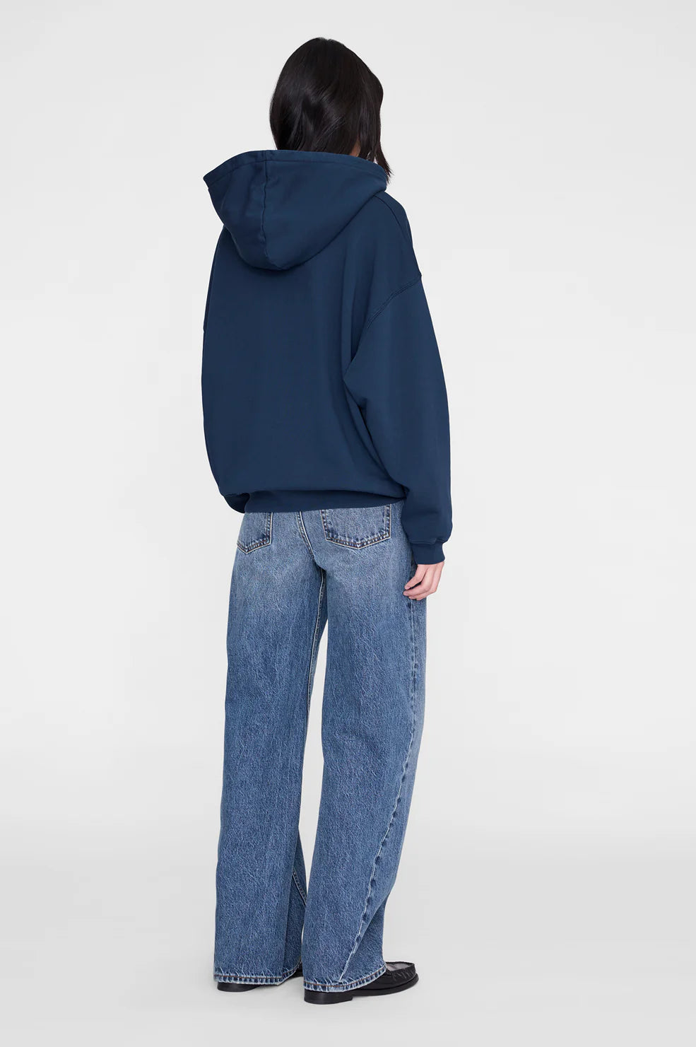 Person wearing a blue hoodie and jeans on a white background