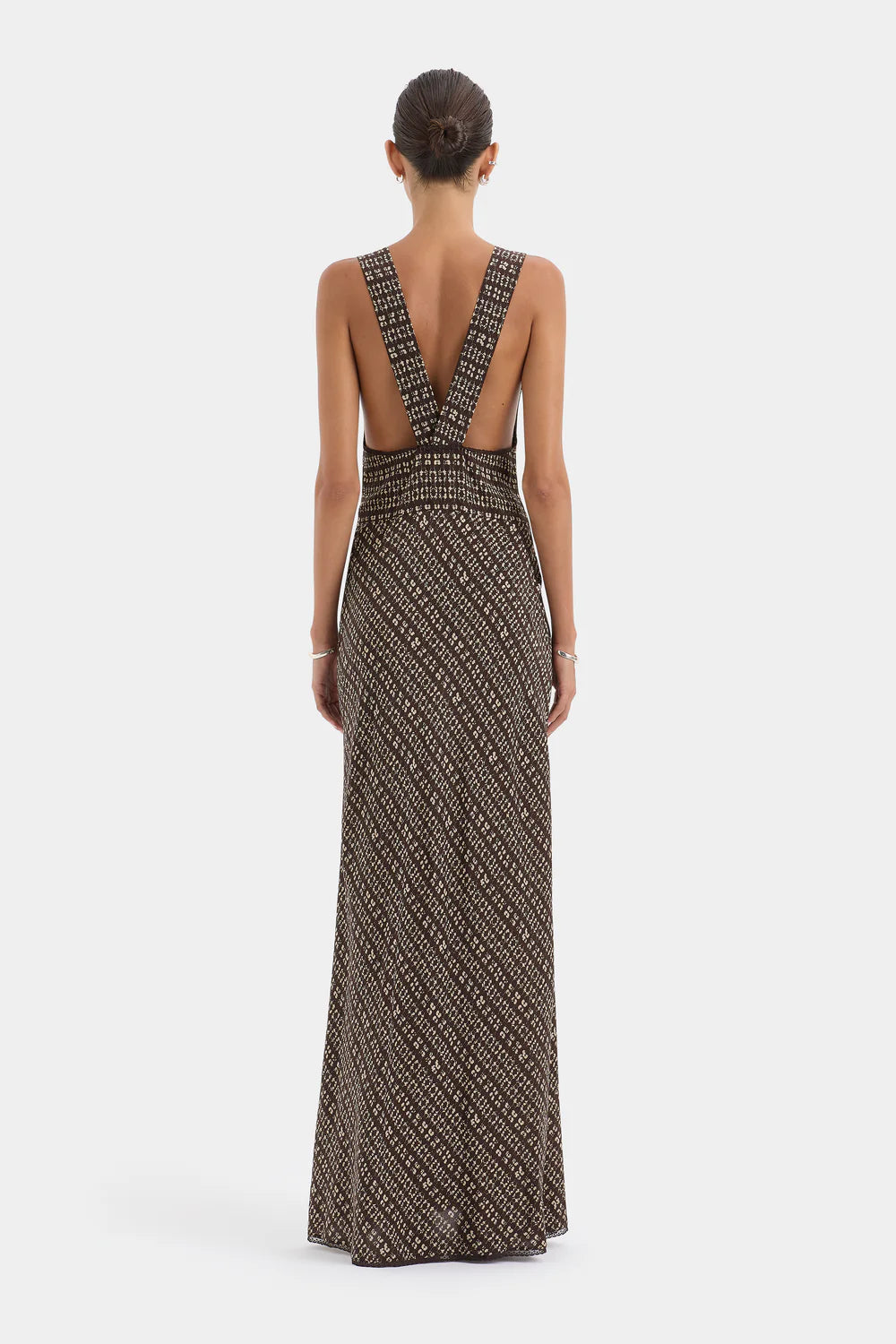 Woman wearing a patterned evening gown with a deep neckline on a white background