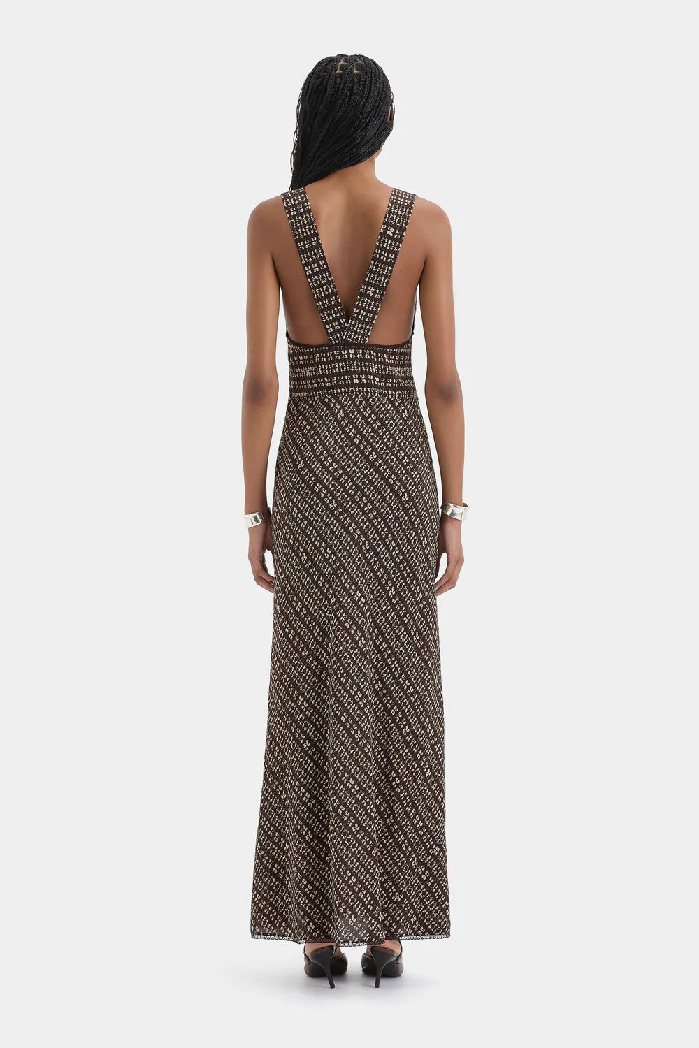 Woman wearing a patterned dress with cut-out back design on a white background