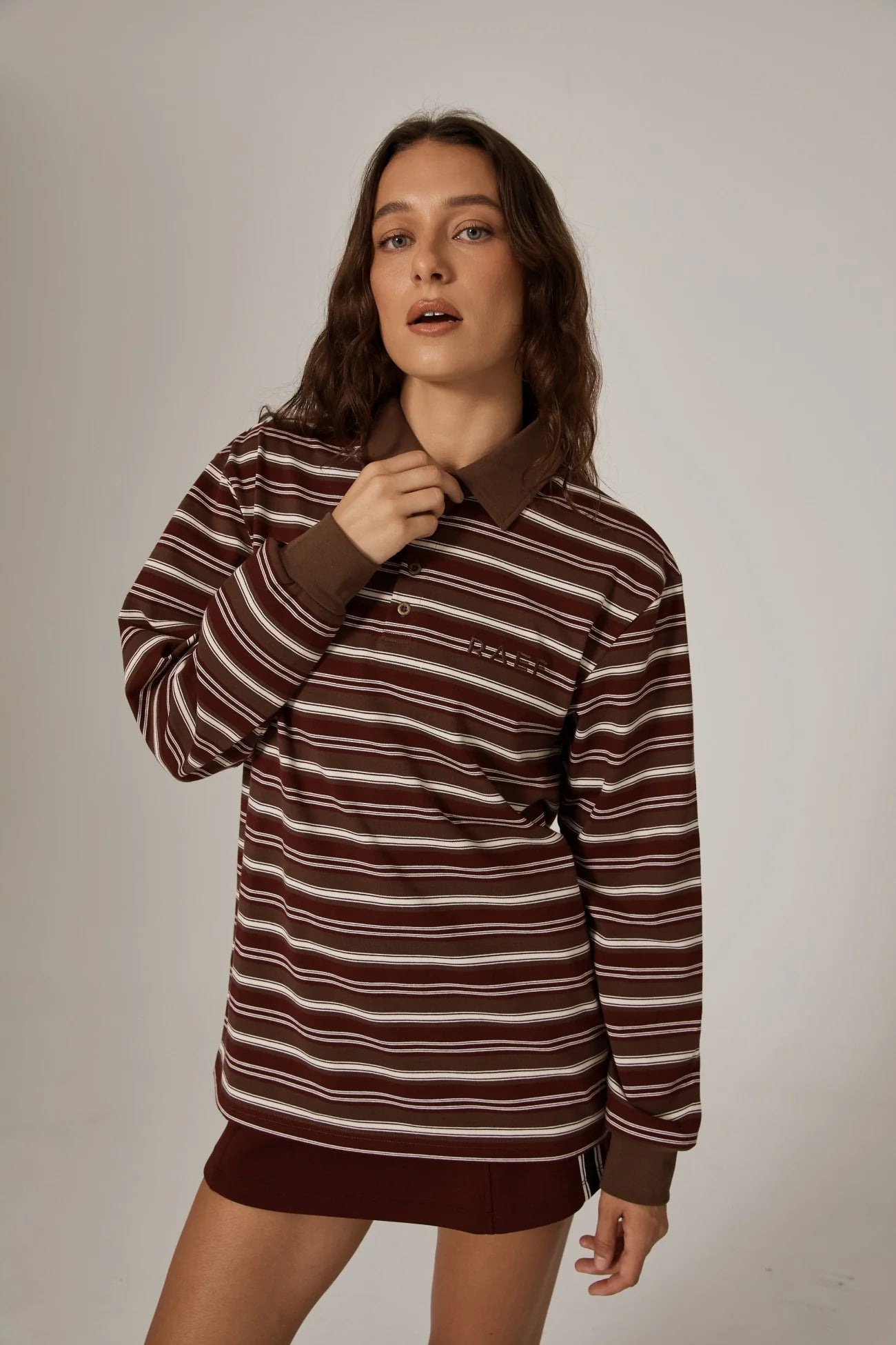Woman wearing a brown and white striped sweater dress against a plain background