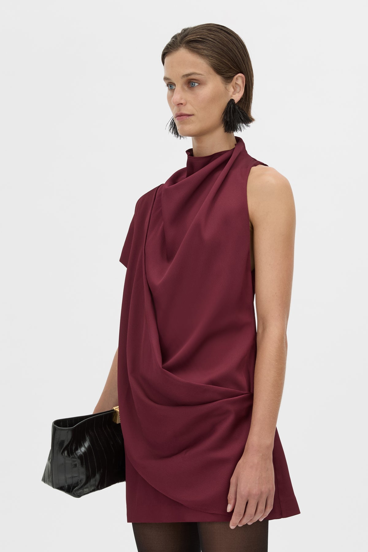 Woman wearing a burgundy dress with a draped design on a white background