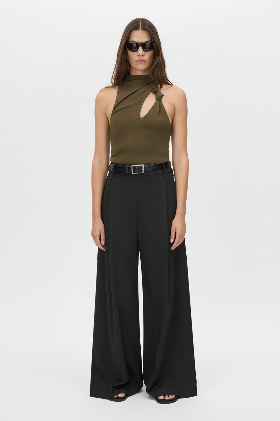 Woman wearing a green halter top and black wide-leg pants on a white background