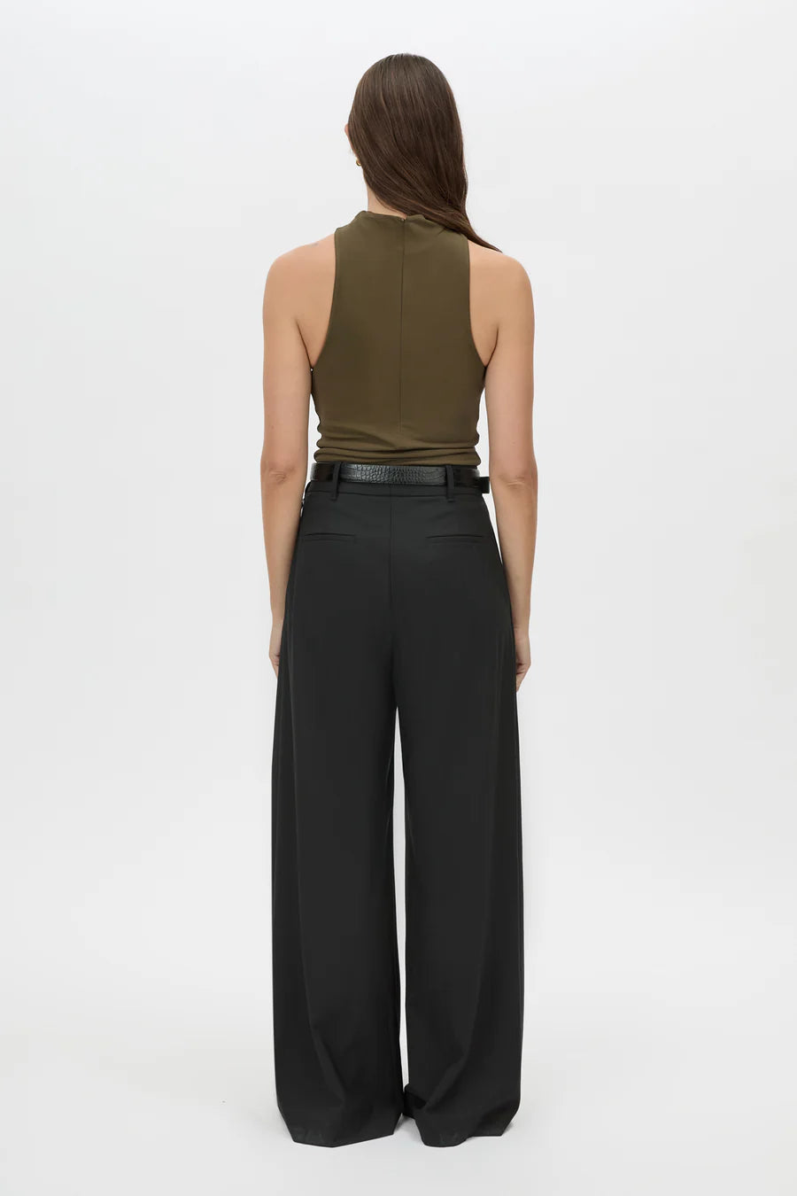 Woman wearing a green sleeveless top and black wide-leg pants on a white background