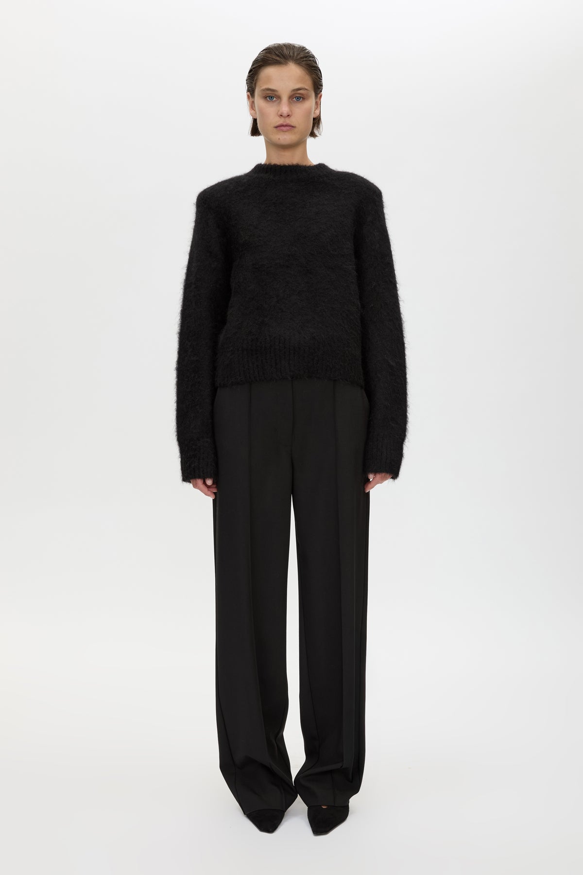 Person wearing a black sweater and pants on a white background