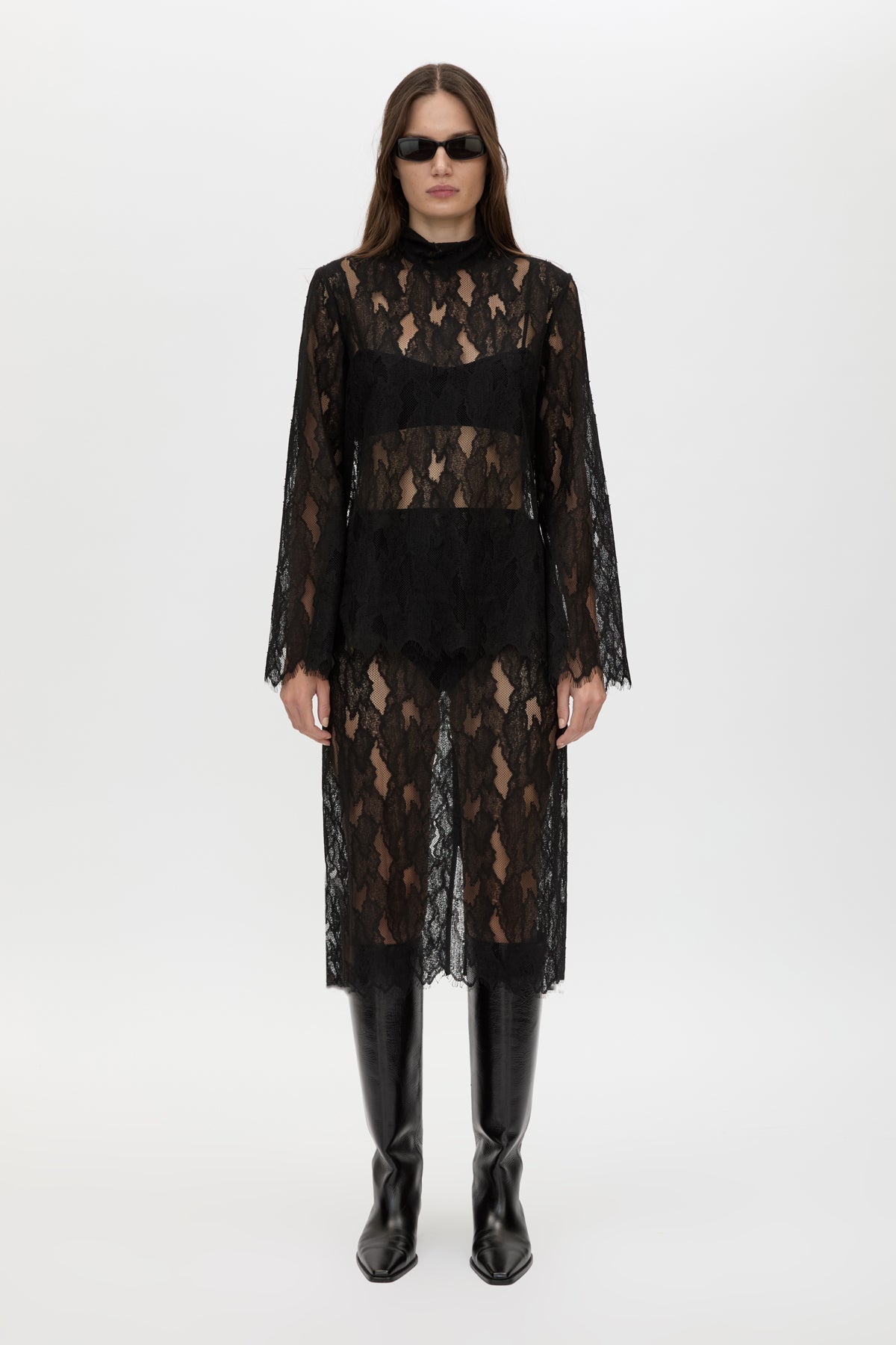 Woman wearing a black lace outfit with sunglasses on a white background