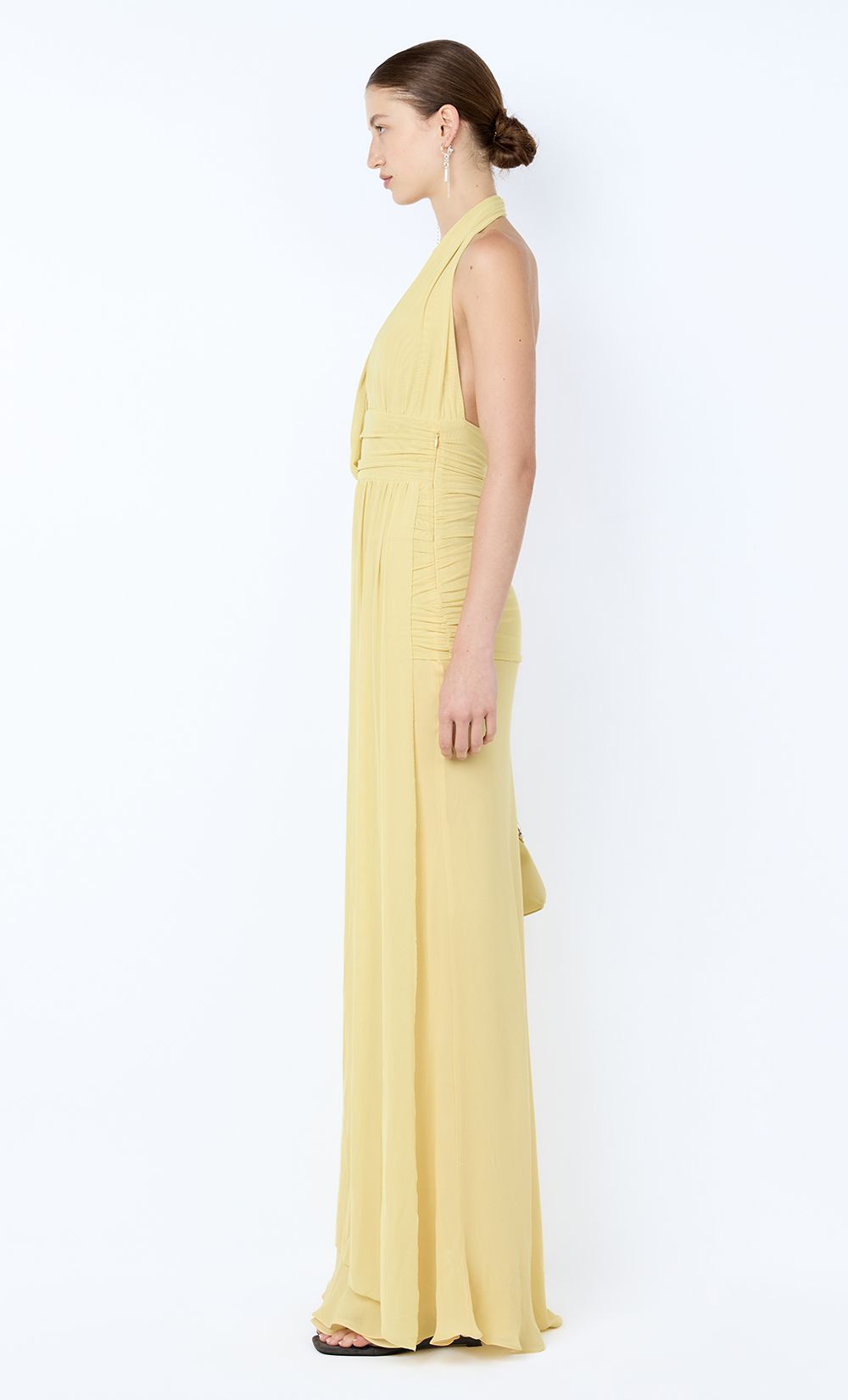 Woman wearing a yellow halter neck dress on a white background