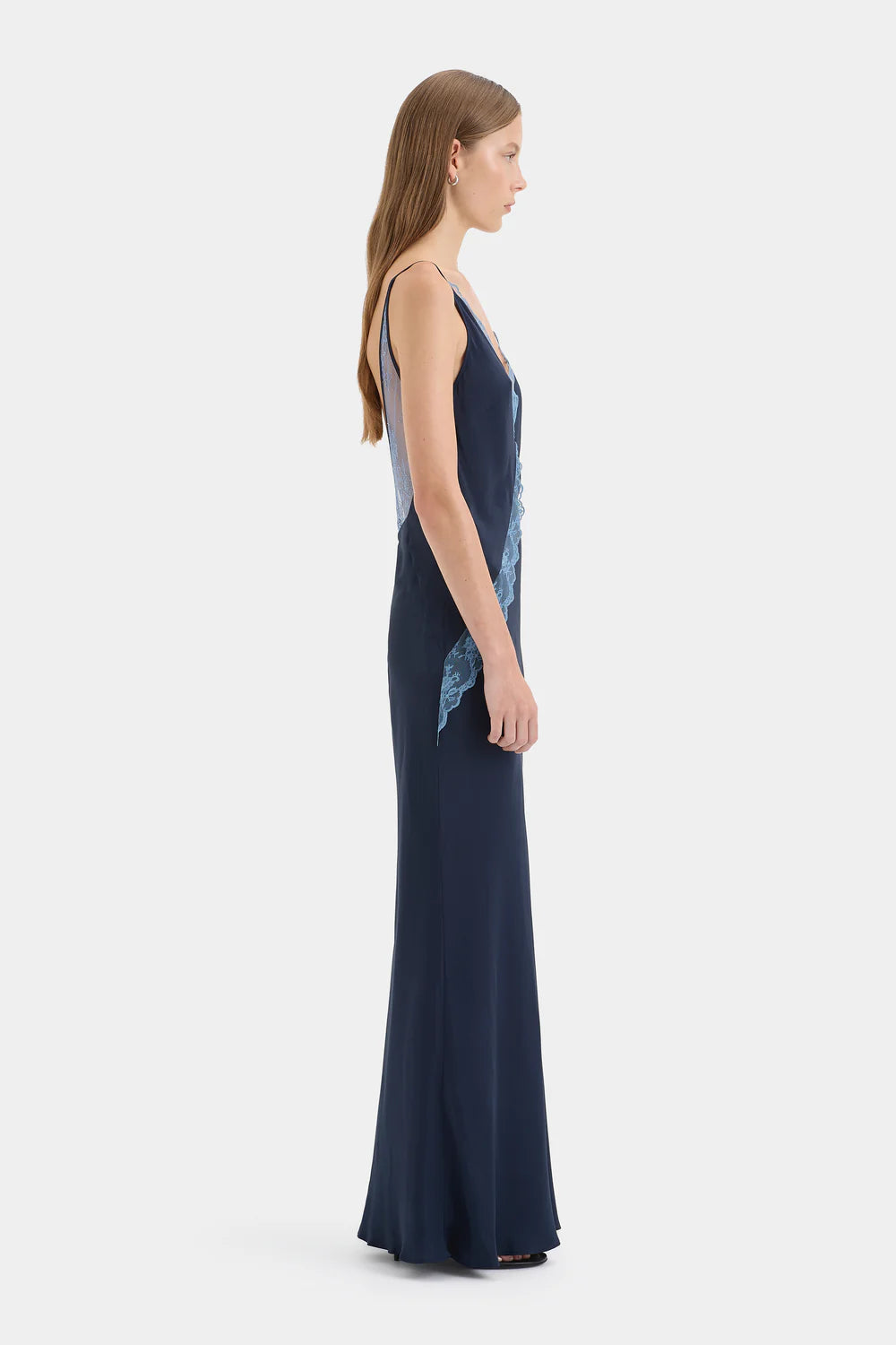 Woman wearing a long navy dress with a white background