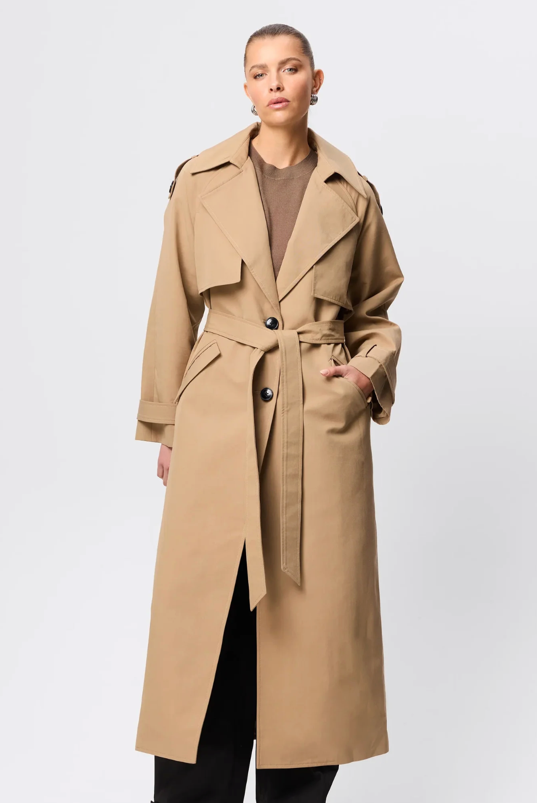 Woman wearing a beige trench coat on a white background