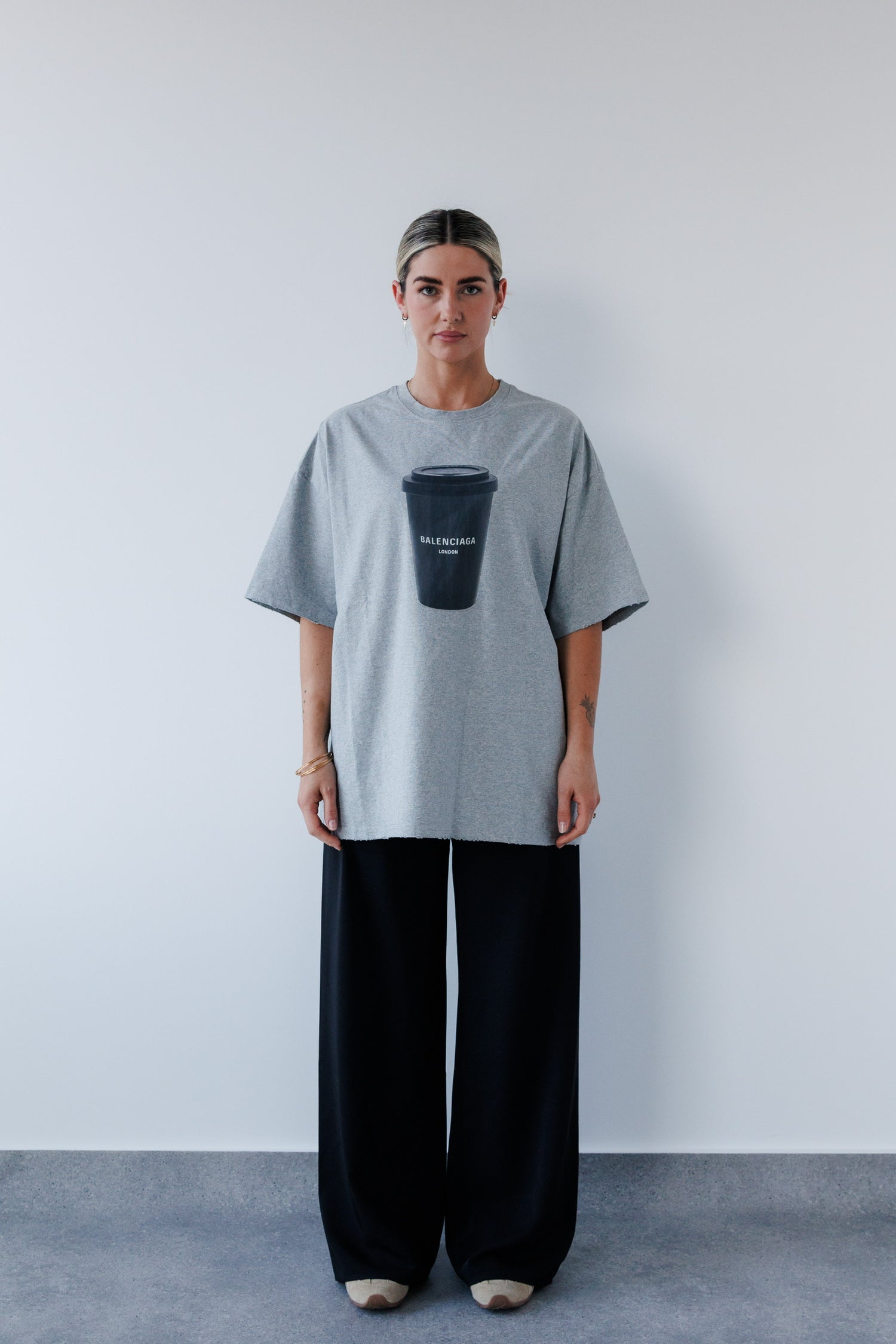 Person wearing a gray oversized t-shirt with a graphic design on a plain background