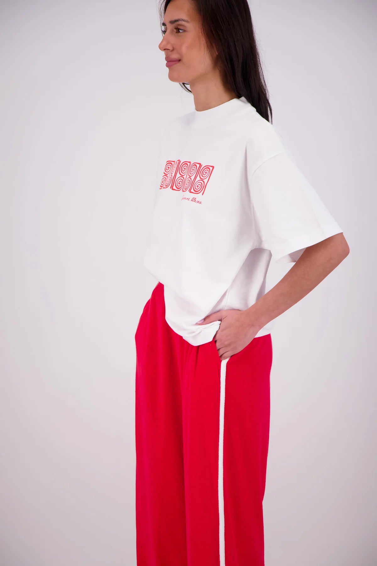 Woman wearing a white oversized t-shirt with red text and red pants on a white background