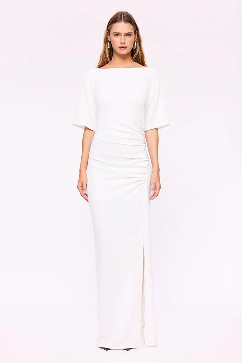 Woman wearing a white off-shoulder dress on a light pink background