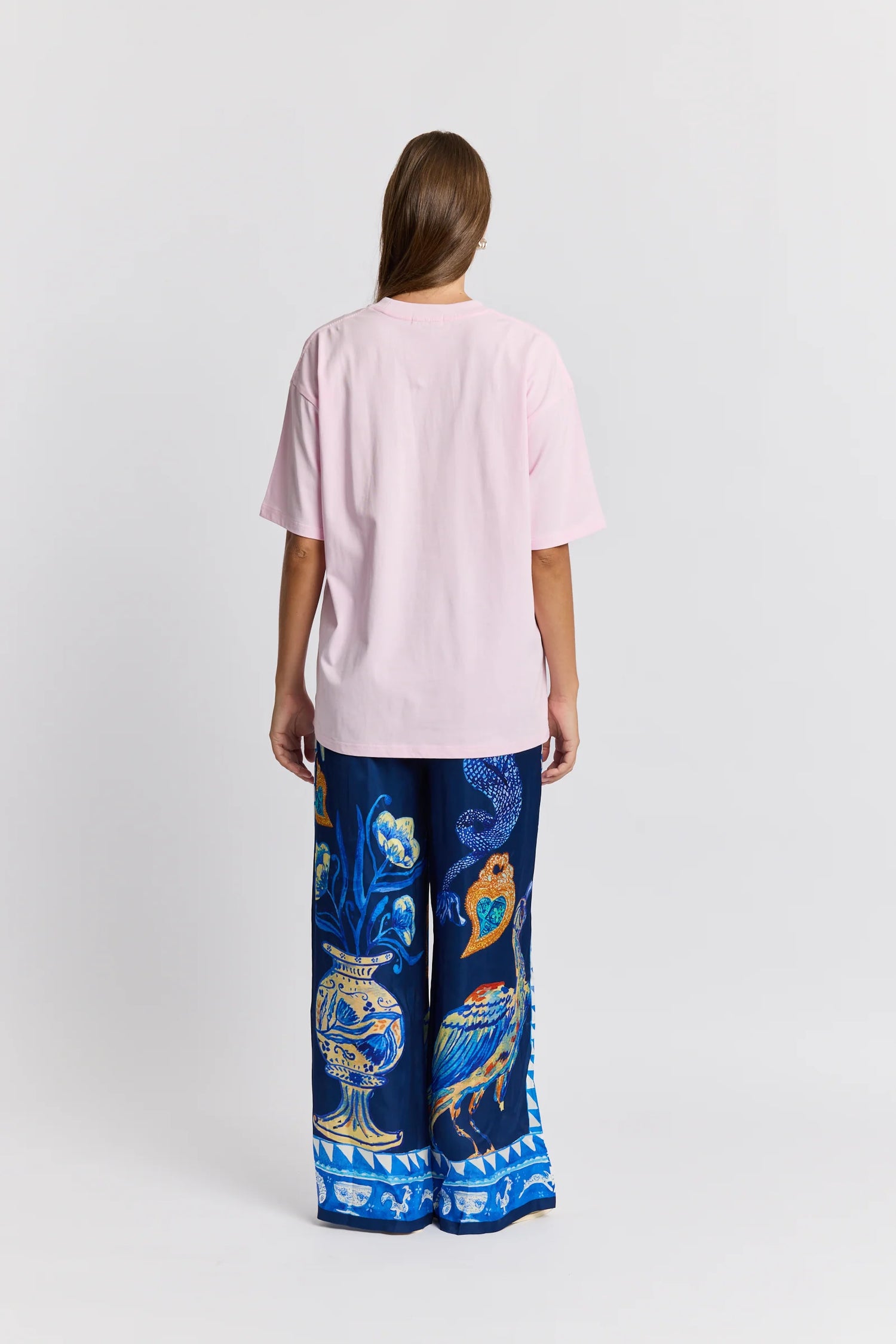 Person wearing a pink t-shirt and blue patterned pants on a white background