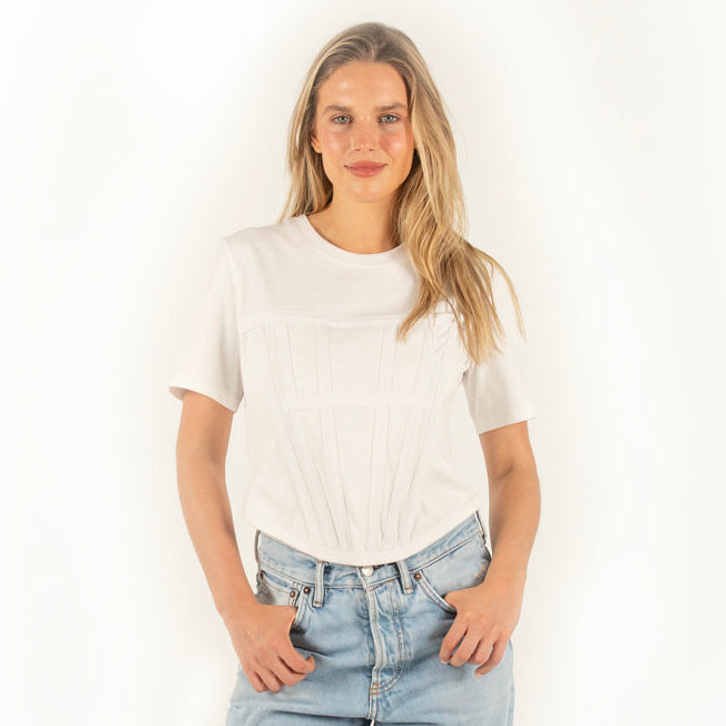 Woman wearing a white corset t-shirt and light blue jeans on a white background