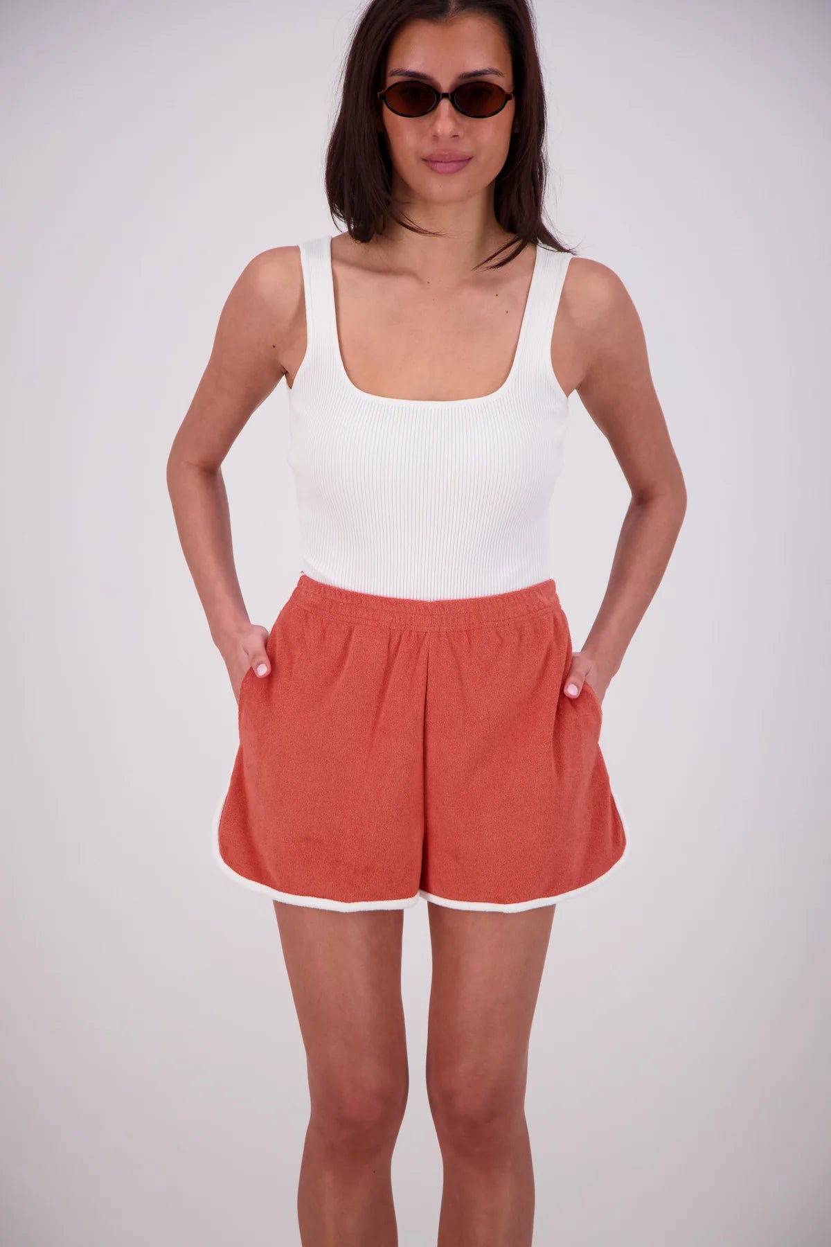 Woman wearing a white tank top and red shorts on a white background