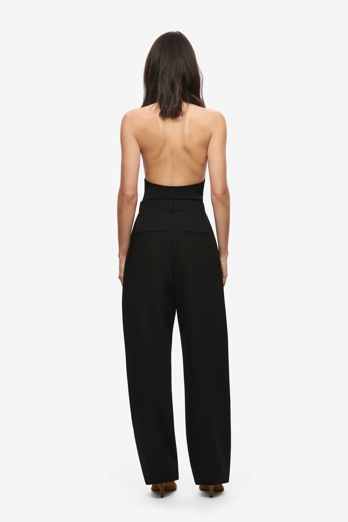 Person wearing a black strapless top and high-waisted pants on a white background