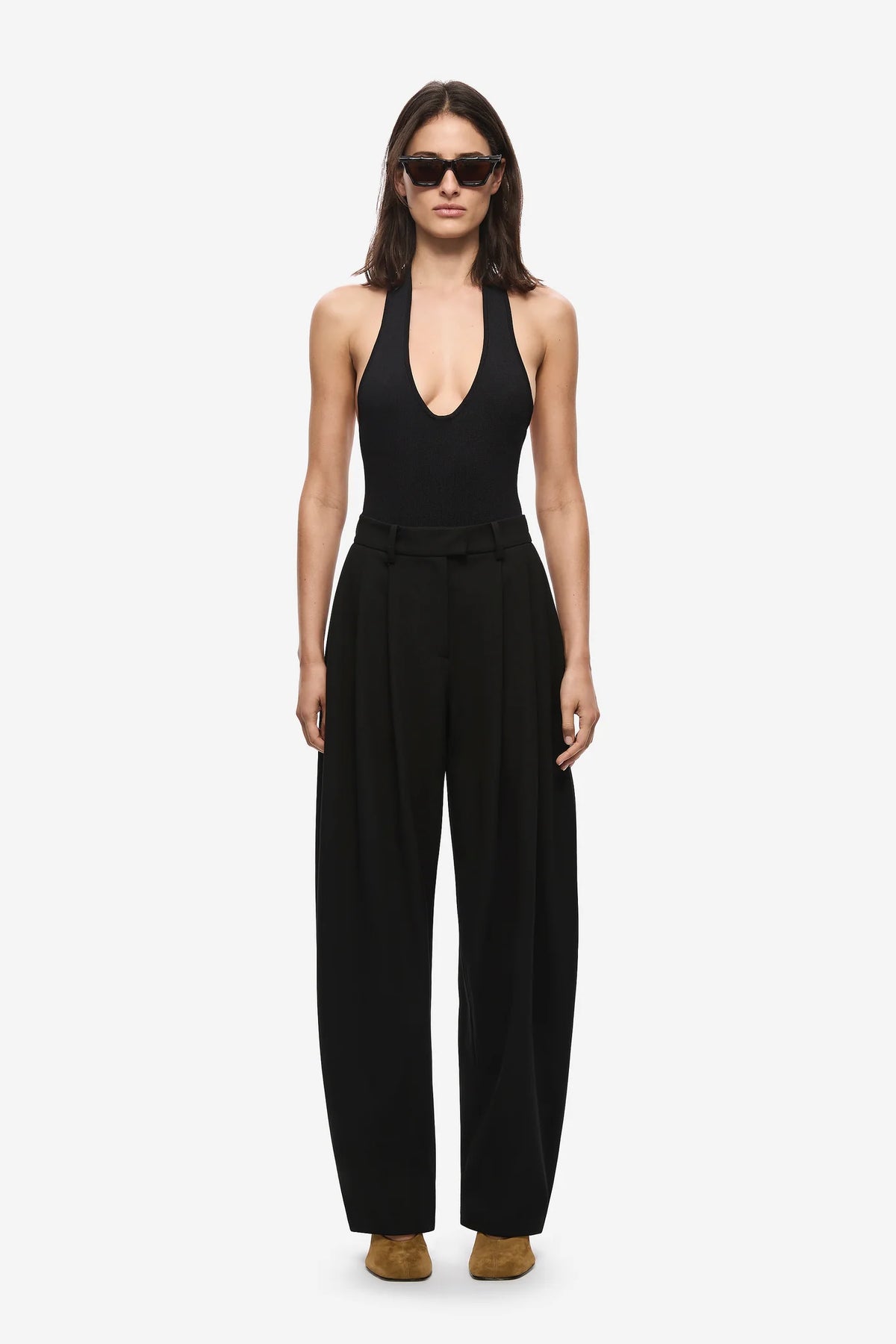 Woman wearing a black barrel leg pants on a white background