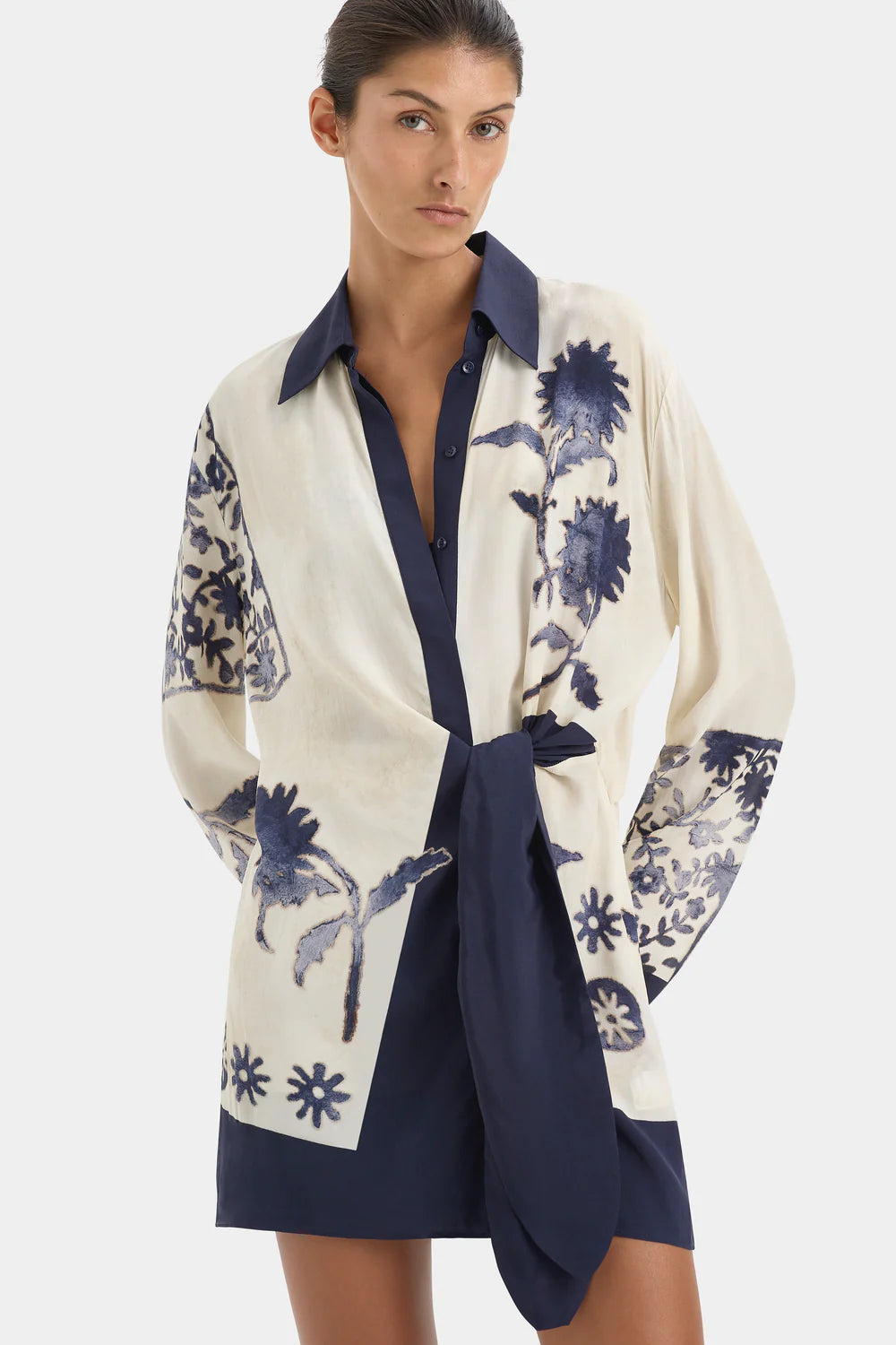 Woman wearing a white and blue floral patterned dress with a plain background
