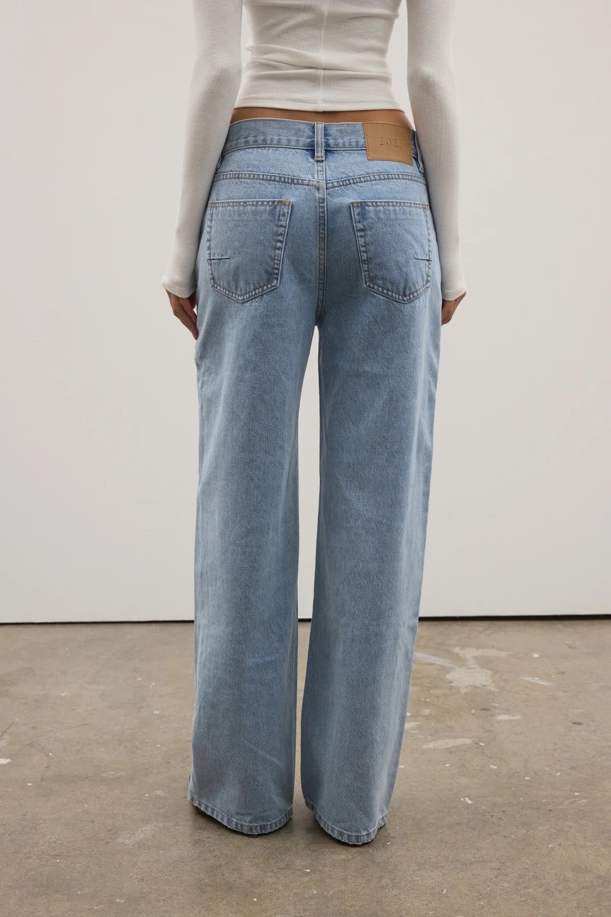 Person wearing light blue jeans with a plain background