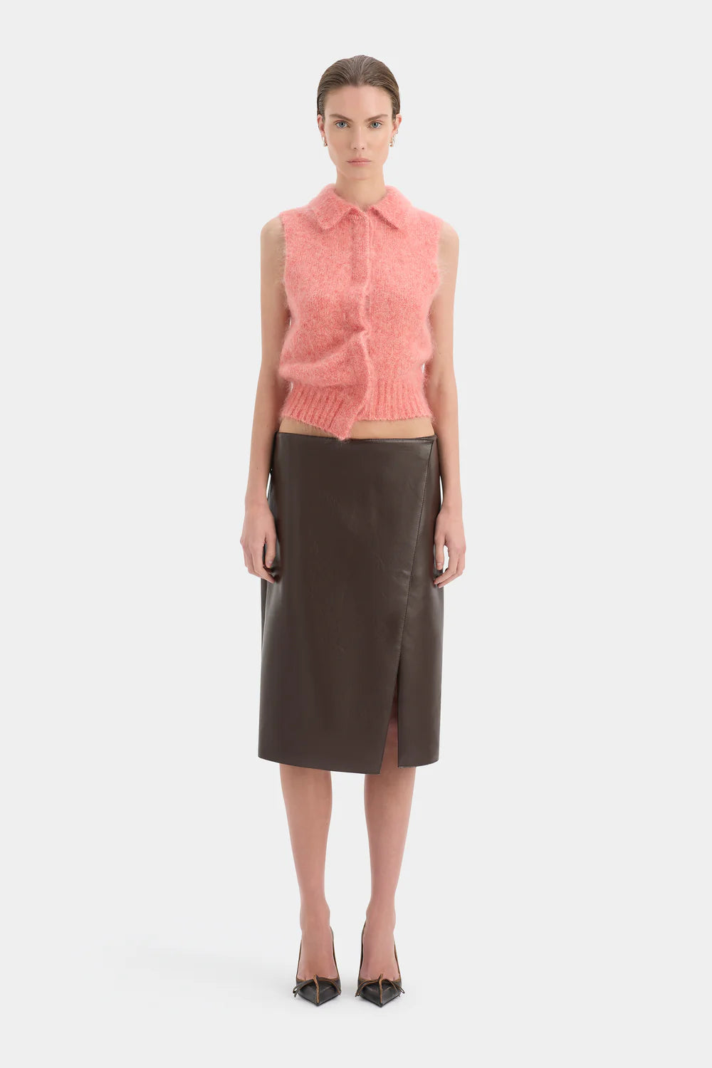 Woman wearing a pink sleeveless top and brown leather skirt on a white background