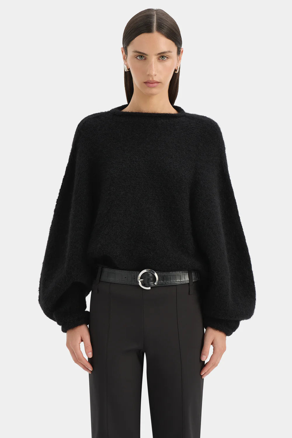 Person wearing a black sweater and black pants on a white background