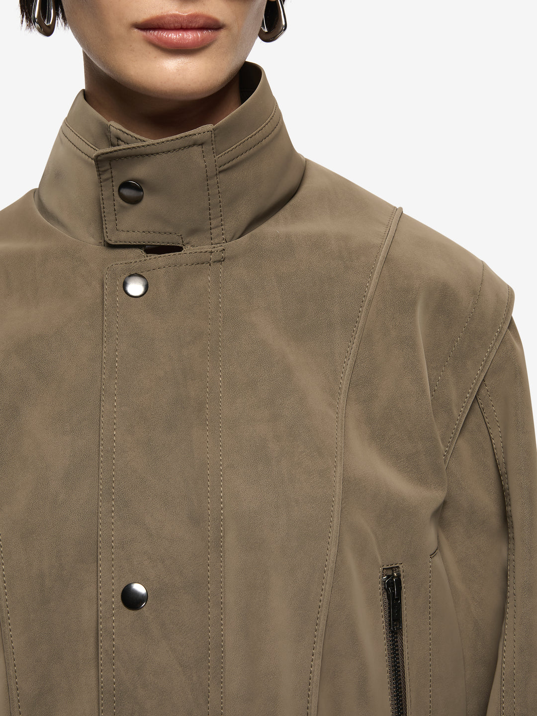 Zoli Bomber in Olive. A chic faux-suede bomber perfect for layering. Designed with panel detailing, internal wadding for warmth, elasticated waistband, and metal press-stud closures, combining structure with relaxed comfort.