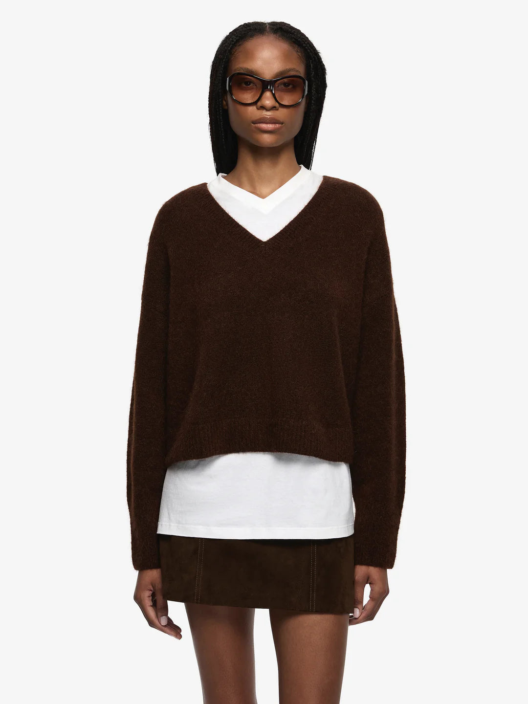 Woman wearing a brown sweater over a white shirt with a white background
