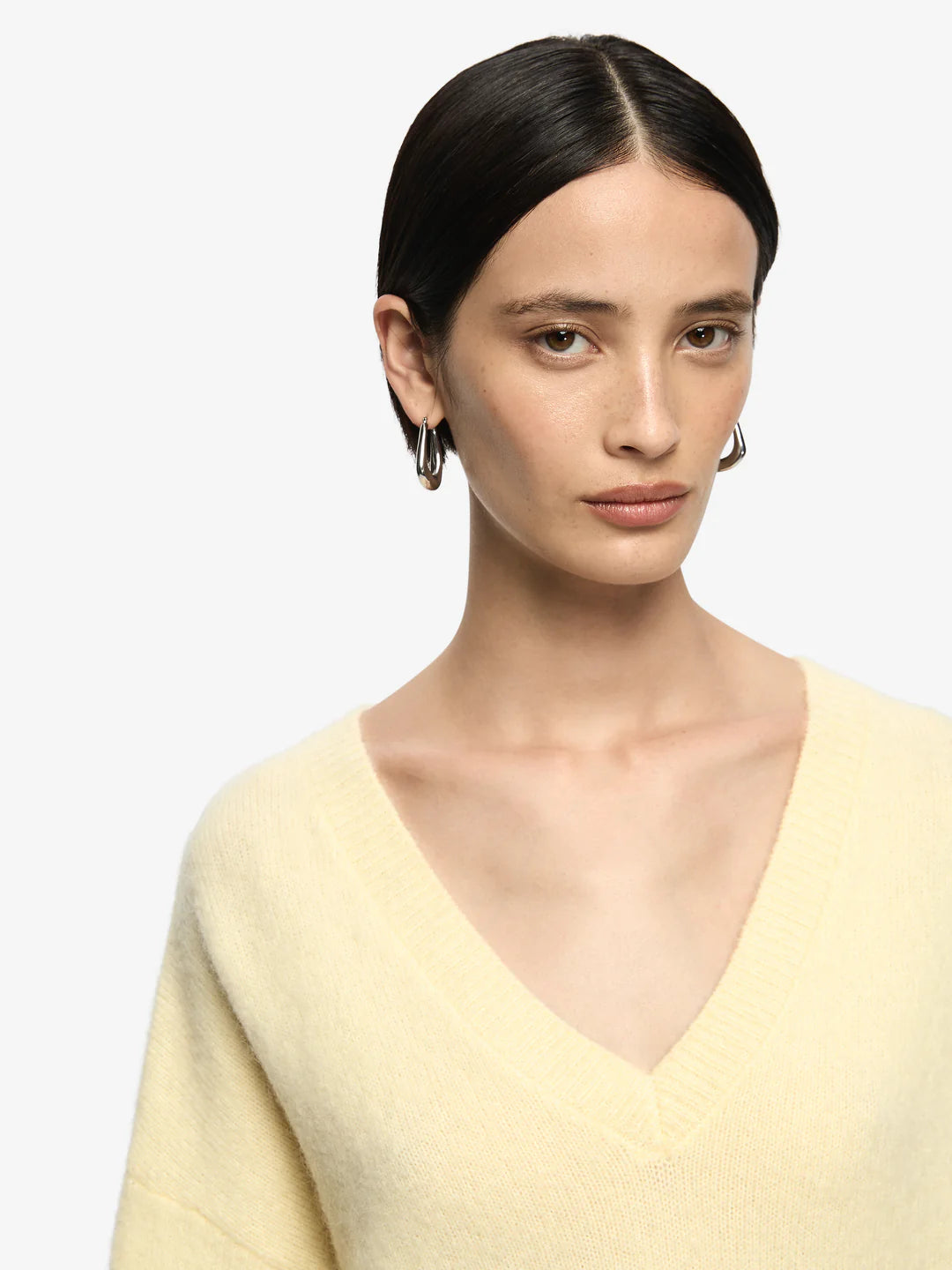 Woman wearing a light yellow sweater against a white background