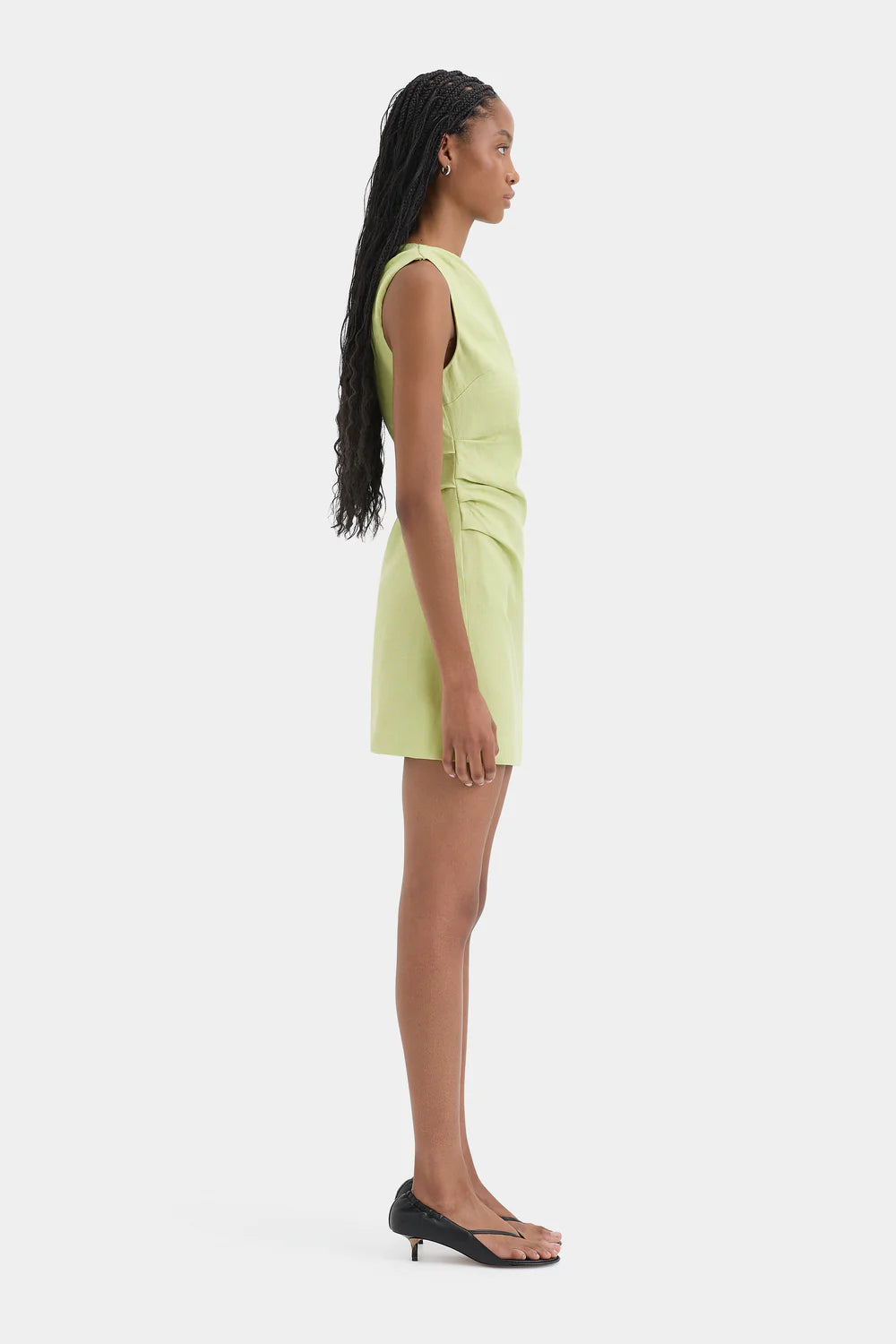 Woman wearing a light green sleeveless dress on a white background