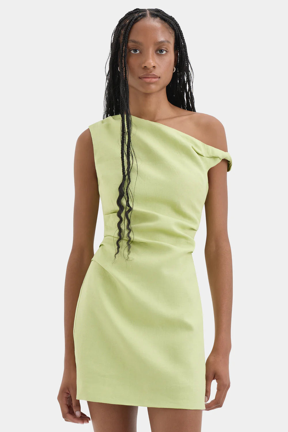 Woman wearing a light green one-shoulder dress on a white background