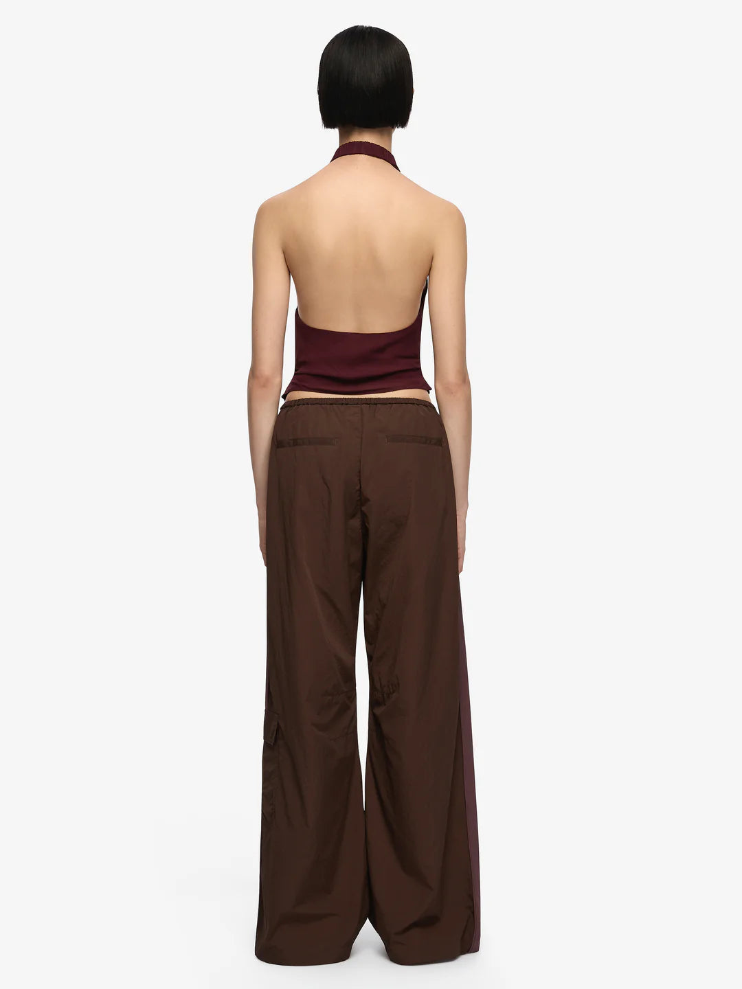 Woman wearing a burgundy halter top and wide-leg pants on a white background