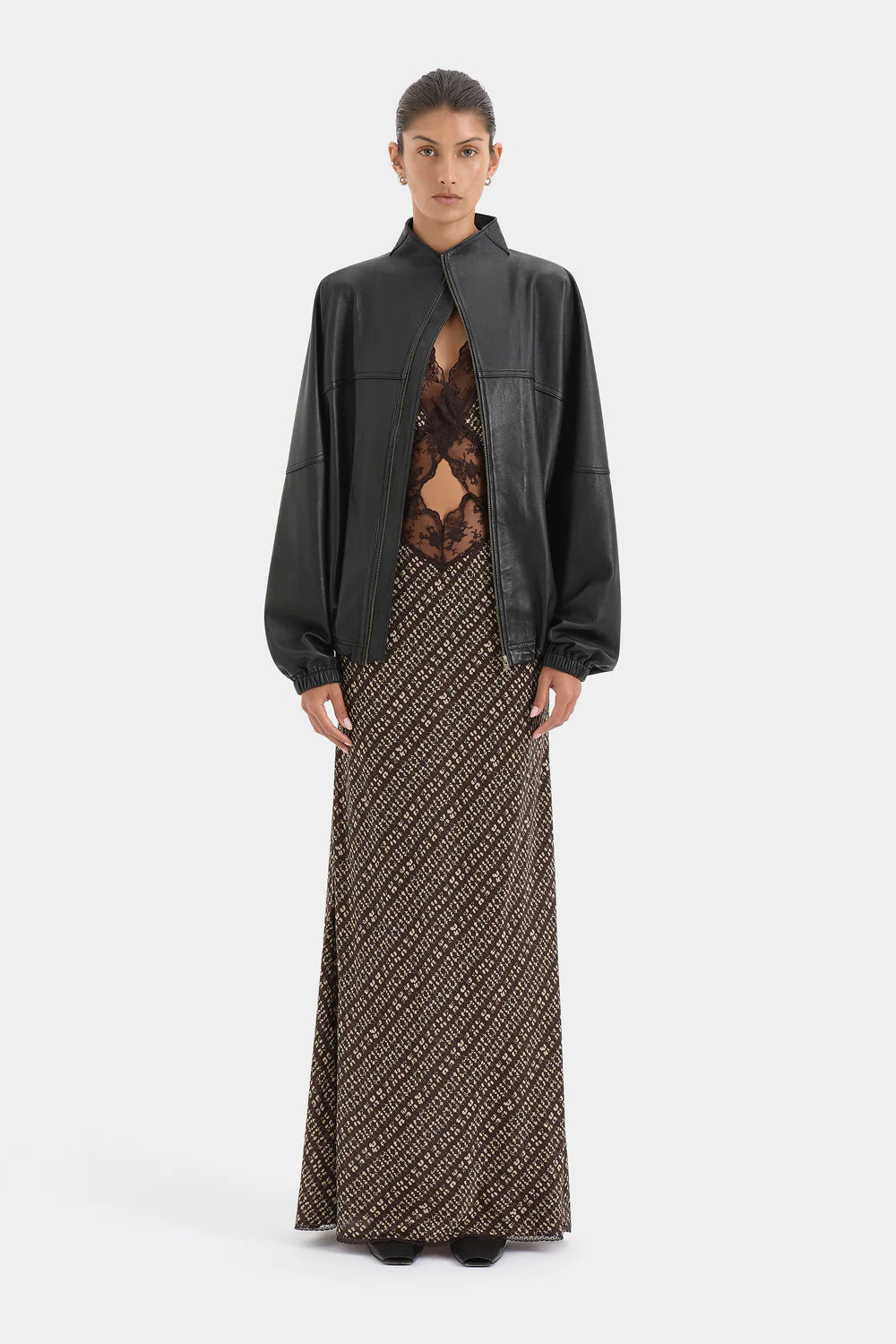 Woman wearing a black jacket over a patterned dress on a white background