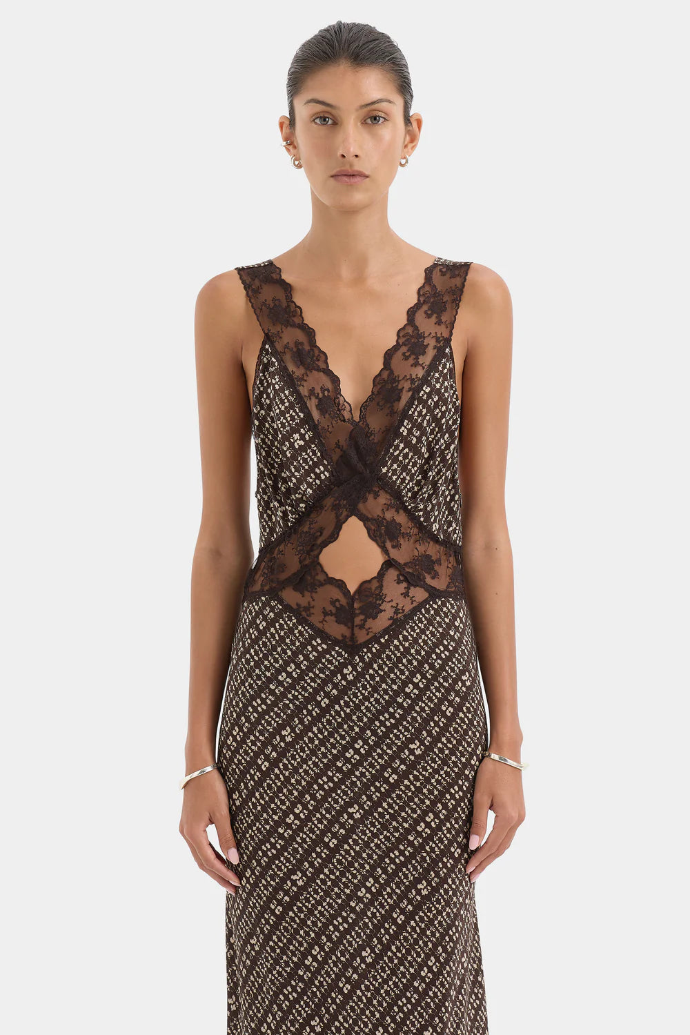 Woman wearing a patterned dress with lace detailing on a white background