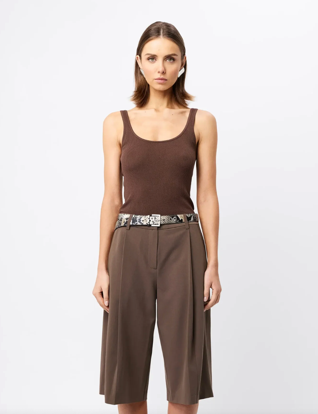 Woman wearing a brown sleeveless top and wide-leg pants on a white background