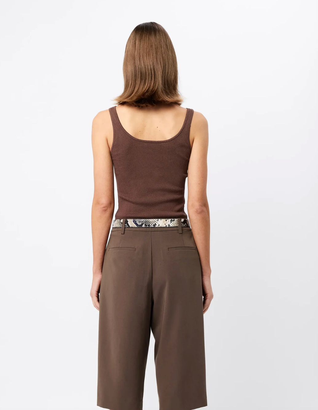 Woman wearing a brown tank top and wide-leg pants on a white background