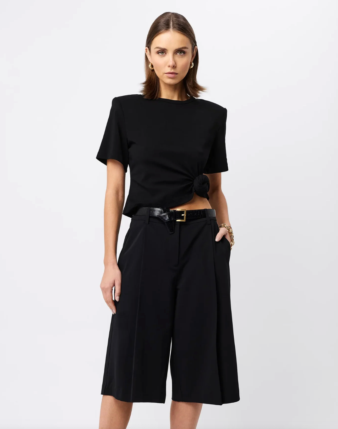 Woman wearing a black Fashion Tshirt with shoulder pads with a white background