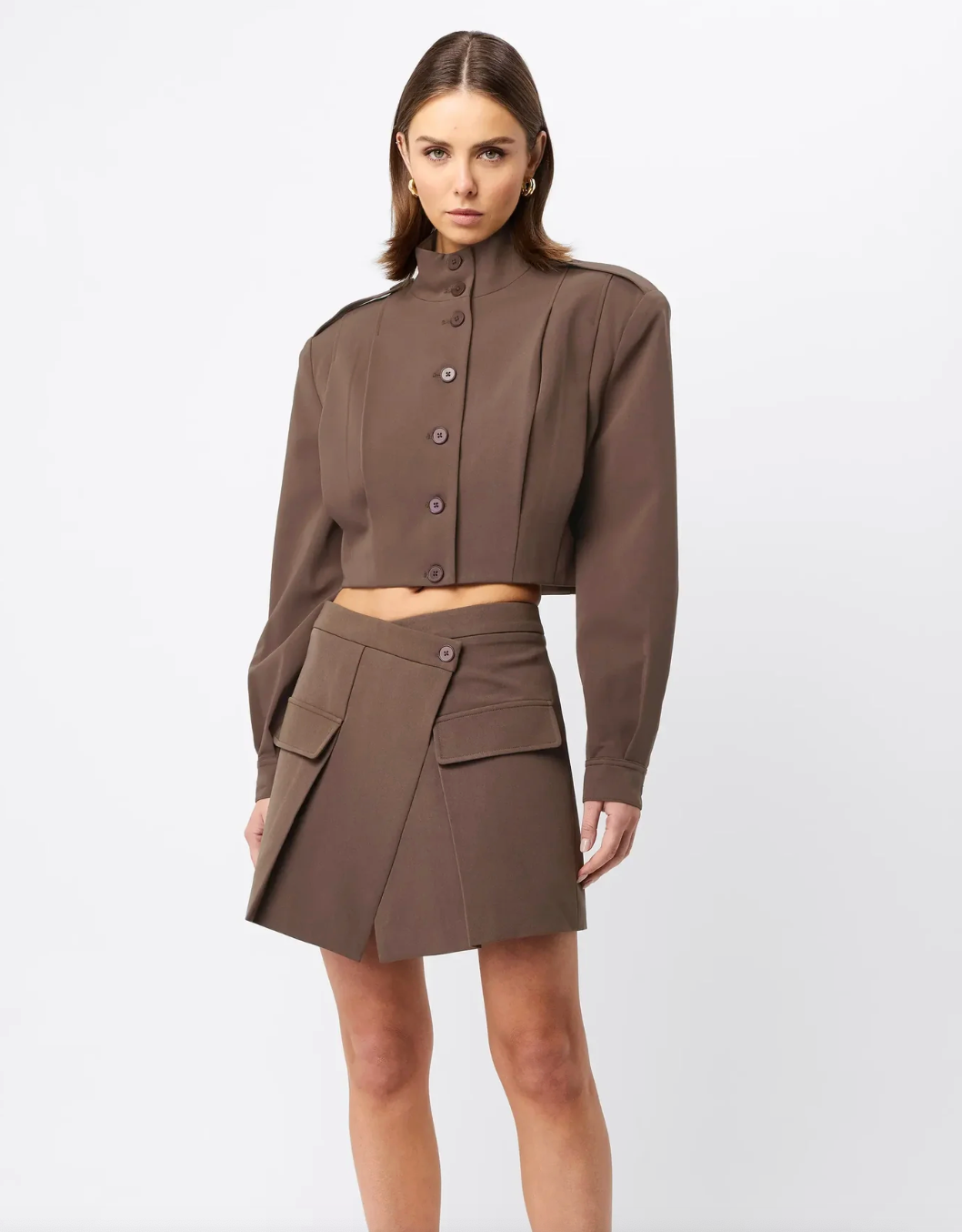 Woman wearing a brown outfit with a jacket and skirt on a white background