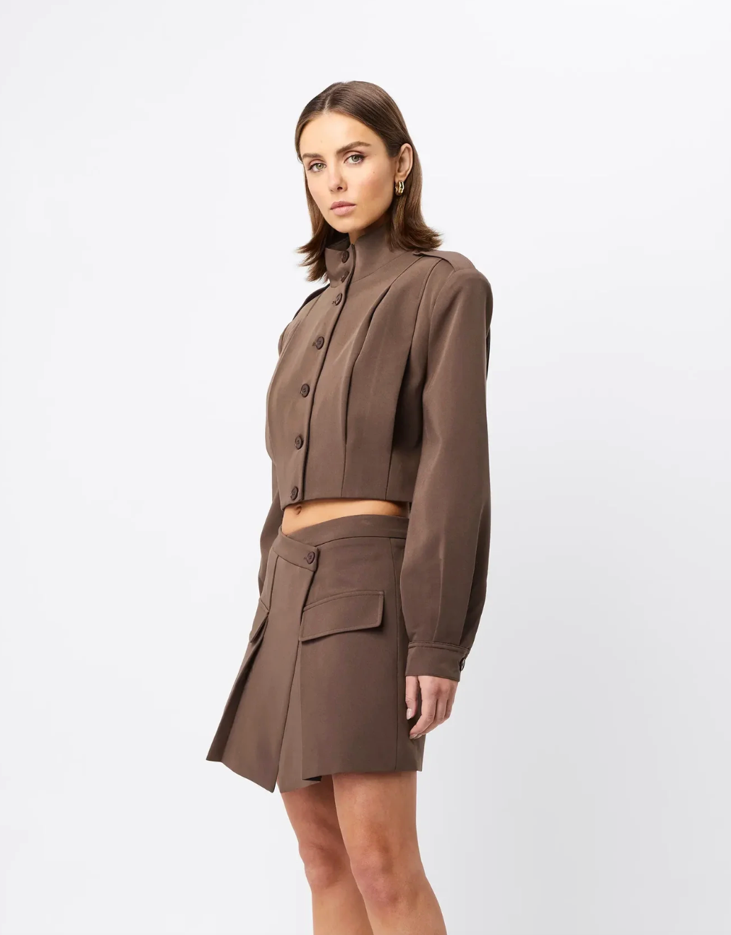 Woman wearing a brown outfit with a jacket and skirt on a white background