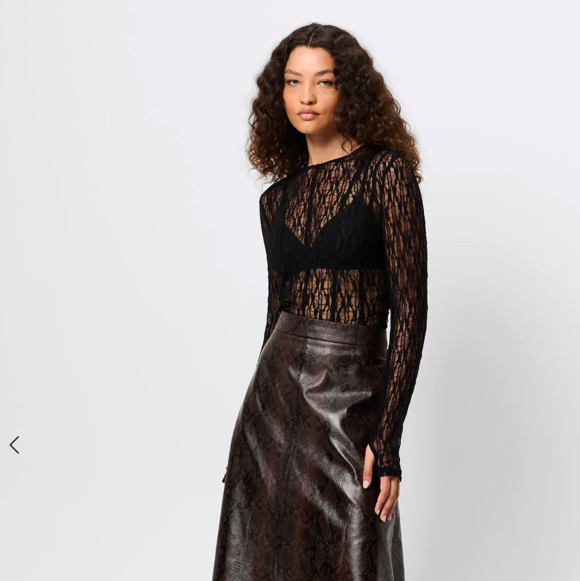 Woman wearing a black lace top and leather skirt on a white background