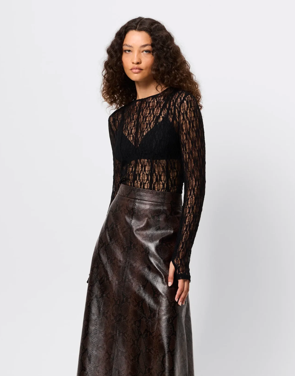 Woman wearing a black lace top and leather skirt on a white background