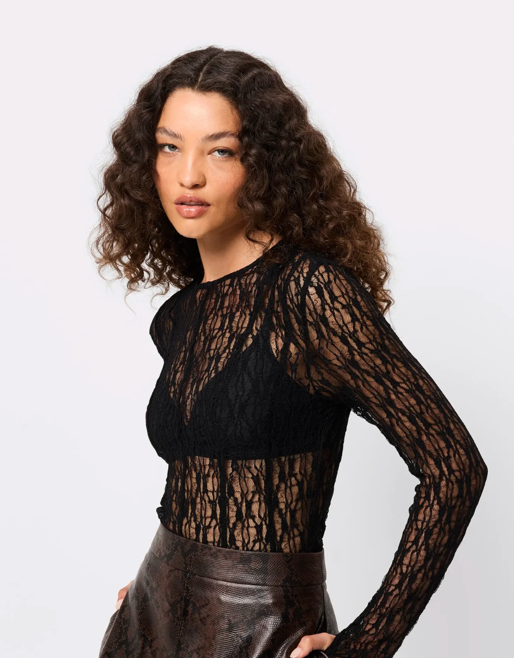 Woman wearing a black lace long-sleeve top against a white background