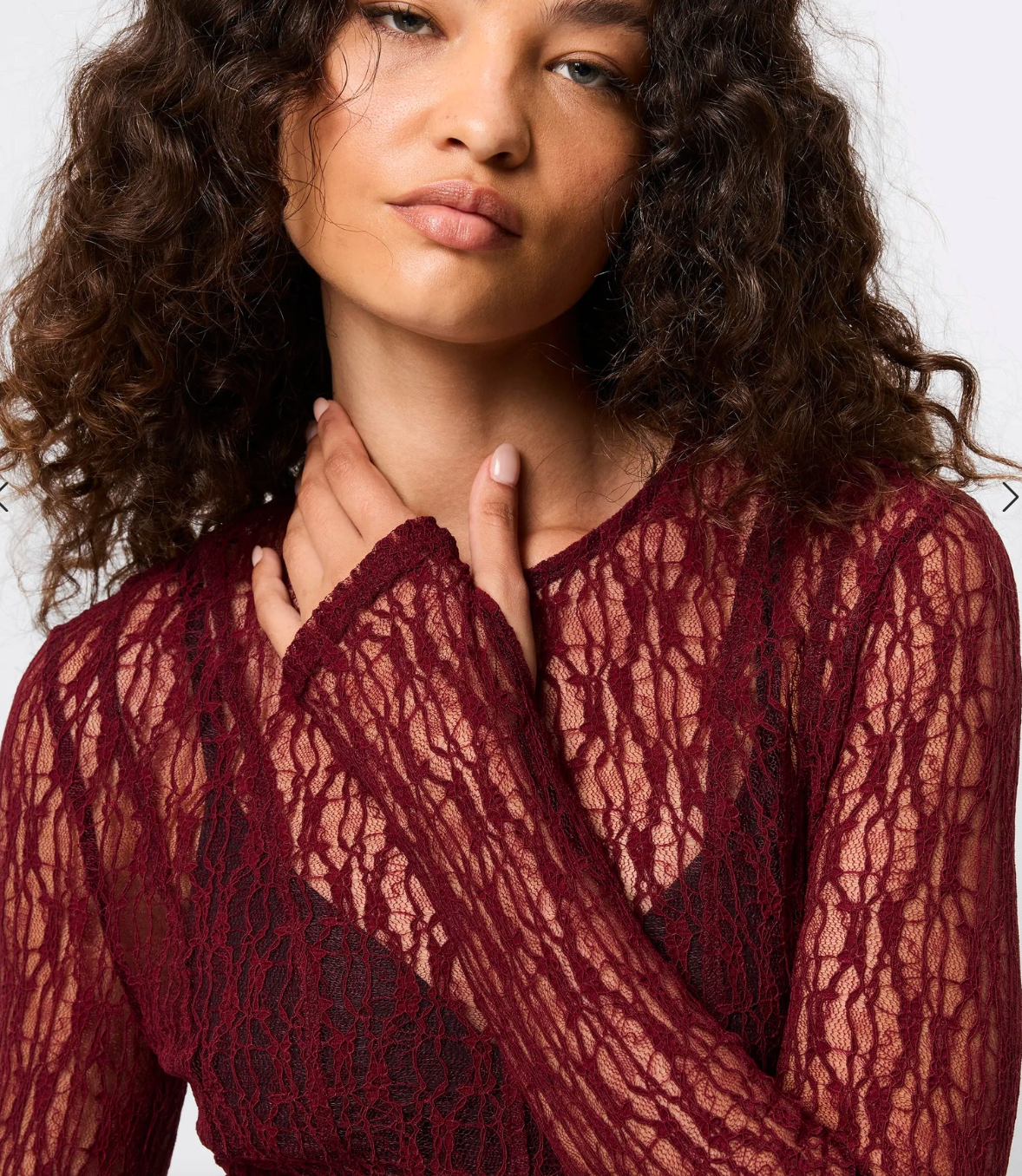 Woman wearing a red lace top against a white background