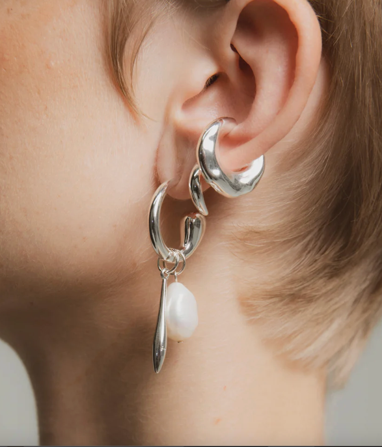 Silver earrings with a pearl drop worn by a person