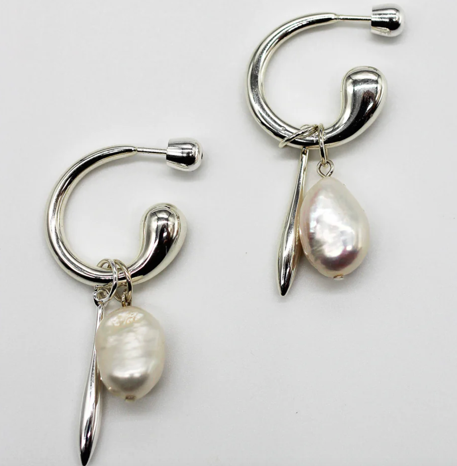 Silver hoop earrings with pearl drops on a white background