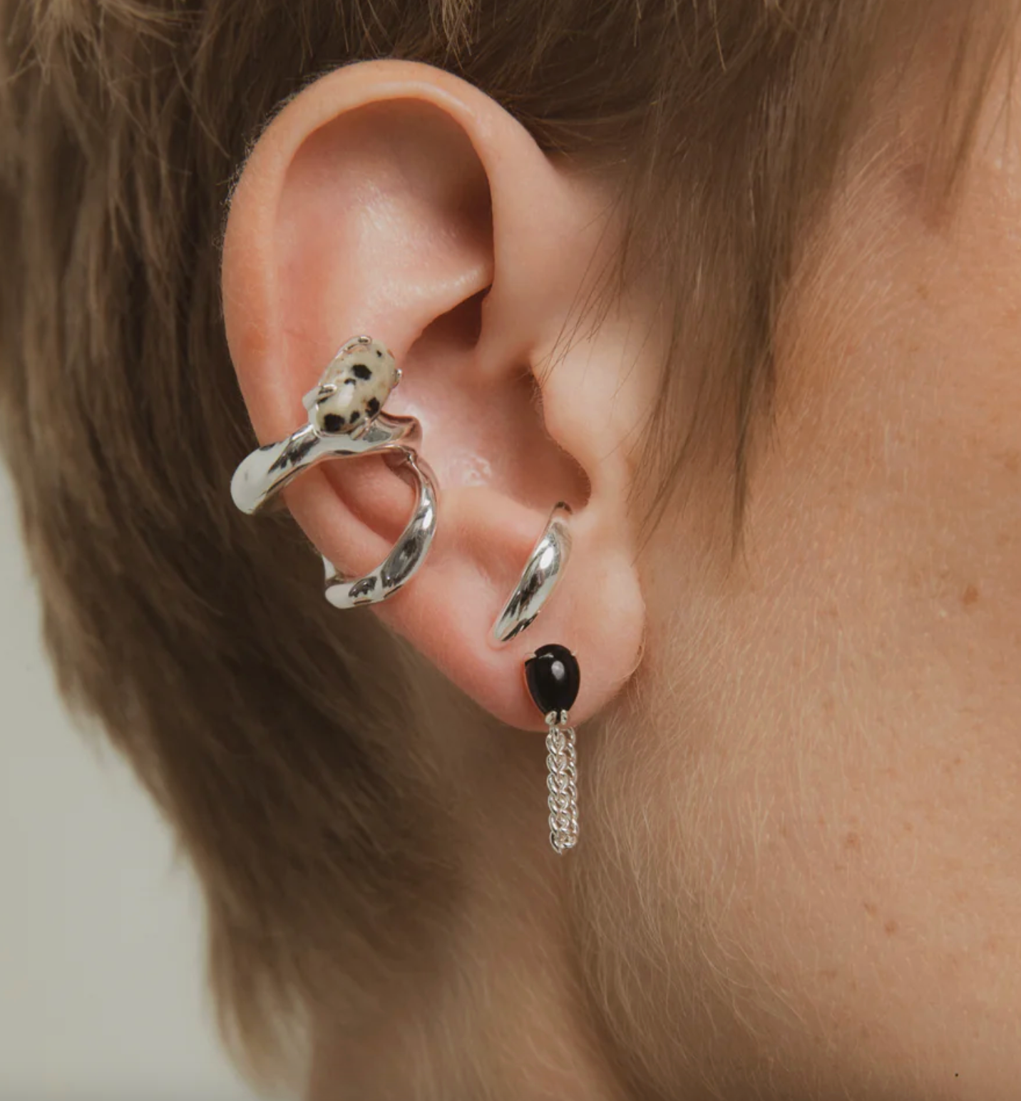 Close-up of an ear with silver ear cuff and dangling earring.