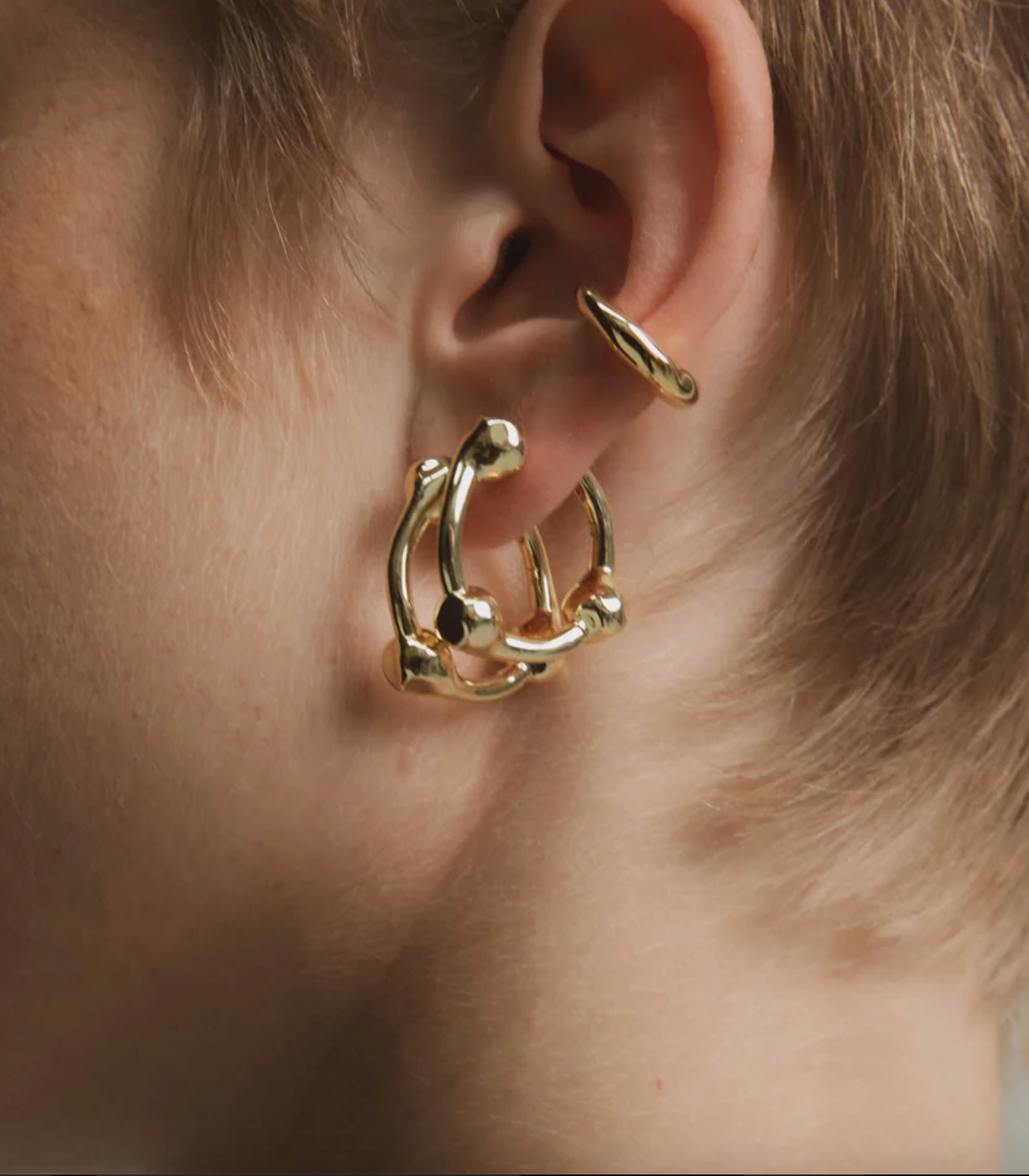 Gold hoop earrings worn by a person with light skin and blonde hair.
