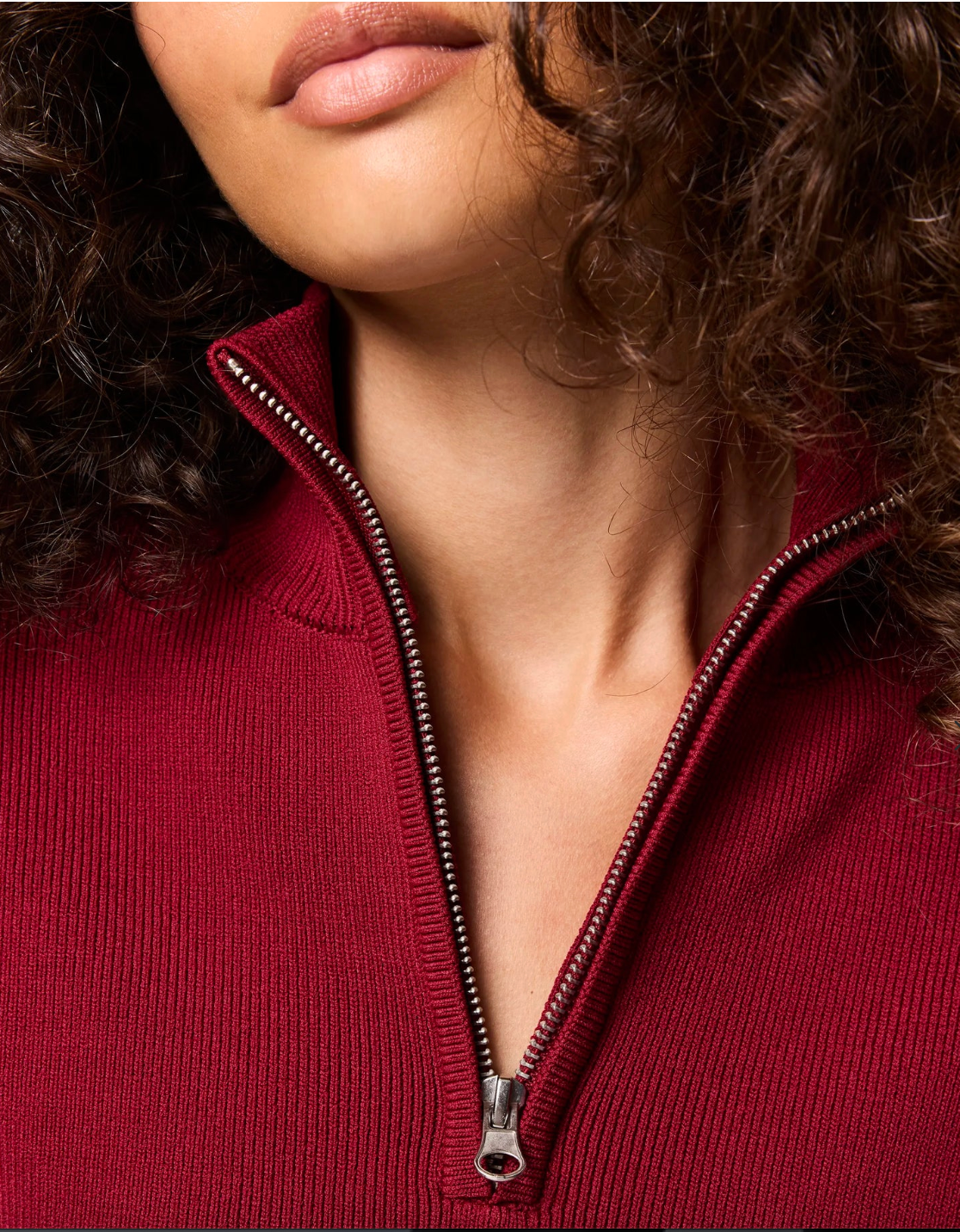 Close-up of a person wearing a red zip-up sweater with a focus on the zipper.